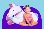 Little girl sitting next to a jumbo plush unicorn from Best Choice from Walmart
