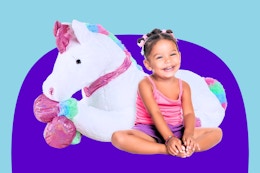 Little girl sitting next to a jumbo plush unicorn from Best Choice from Walmart