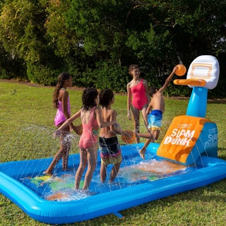 kids playing in an inflatable splash pad with a basketball hoop