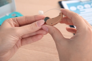 A person holding a hearing aid.
