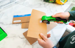 a person using an electric box cutter on cardboard
