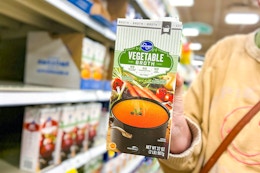 hand holding a carton of kroger broth