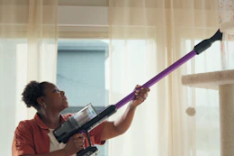 a woman using a bissell vacuum to clean a cat tree