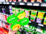 hand holding a 4-count package of Activia Proactive yougurts
