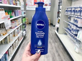 hand holding a bottle of nivea lotion in an aisle at target