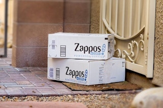 Two Zappos boxes stacked on a front porch.
