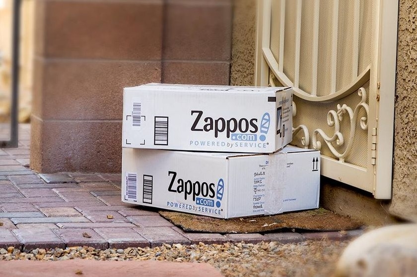 Two Zappos boxes stacked on a front porch.