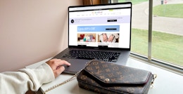 a person browsing the real real website with a purse sitting near their laptop