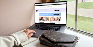 a person browsing the real real website with a purse sitting near their laptop