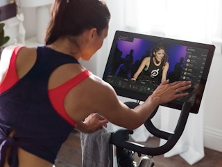 A person on a Peloton exercise bike using the touchscreen