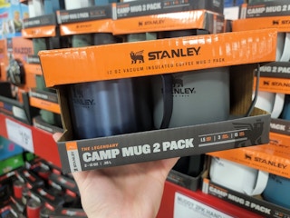 A person's hand holding up a 2-pack of Stanley mugs inside Sam's Club.
