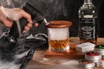 person using whiskey smoker on glass