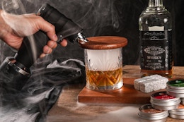 person using whiskey smoker on glass