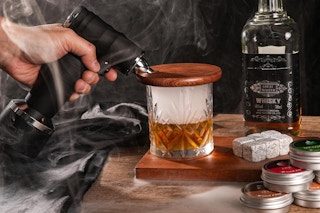 person using whiskey smoker on glass