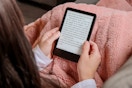 a person reading a kindle while sitting on a couch
