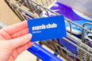 hand holding a sams club membership card over cart