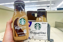 person holding a starbucks frappuccino drink in front of a shelf