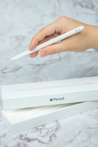 someone holding an apple pencil next to a box