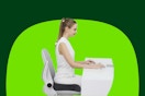 A young woman wearing white sits at a white desk with a white keyboard on a white chair so you'll notice the black seat cushion.