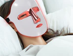 a person with a red light therapy face mask on 
