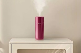 Homedics Portable Ultrasonic Humidifier in the color "Berry" on a piece of furniture