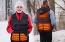 a couple outside wearing a heated vest in the snow