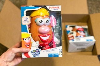 a hand holding a Mrs. Potato Head over a box