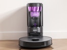 a self-emptying robot vacuum against a wall 