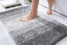 Person stepping on shaggy grey bathroom rug