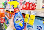 person holding a bottle of oxiclean stain remover by a buy 1 get 2 free sign