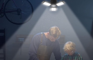 a garage light lit up in a workspace with a father and son