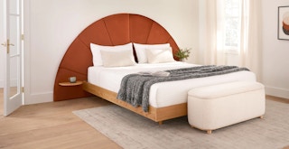 a bedroom with a white bed and storage ottoman