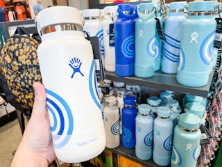 someone holding up a white hydro flask water bottle in the store