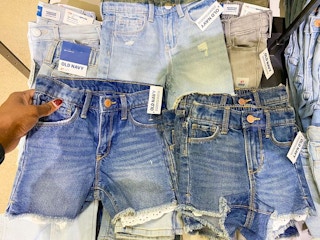 person holding jean shorts on shelf