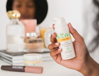 A person holding a lotion pump bottle in front of a vanity