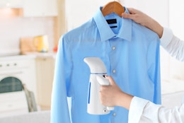 a person using a handheld steamer on a shirt