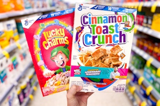 hand holding lucky charms and cinnamon toast crunch cereals