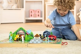 Lifestyle image of the Melissa & Doug Tabletop Train Set being played with by small child on the floor