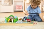Lifestyle image of the Melissa & Doug Tabletop Train Set being played with by small child on the floor