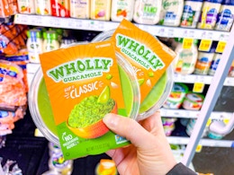 hand holding wholly guacamole tubs