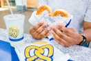 Person holding an Auntie Anne's Pretzel with a lemonade drink