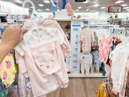 a hand holding up a carter's three piece set in the baby clothing area at kohl's