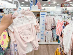 a hand holding up a carter's three piece set in the baby clothing area at kohl's