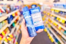 person holding 2 gillette deodorants in an aisle