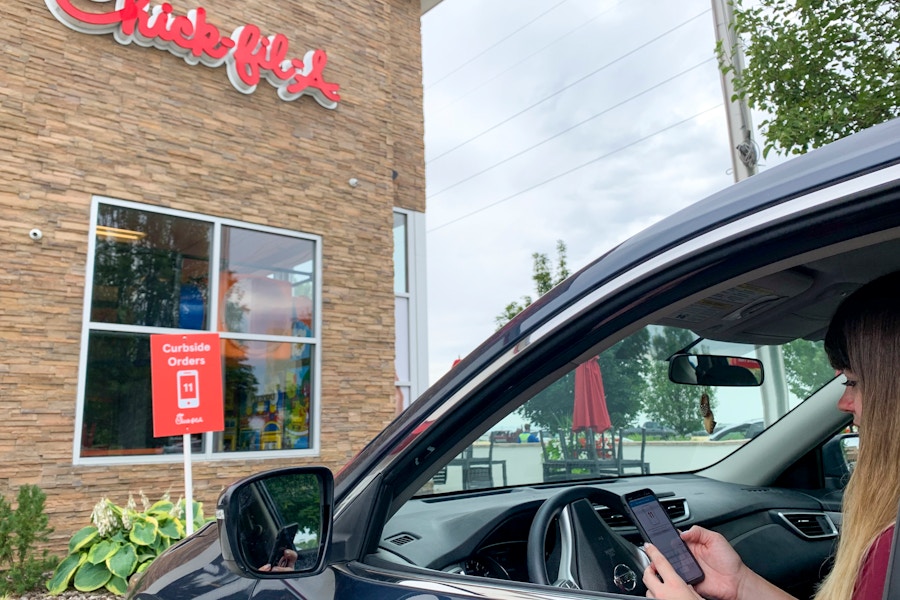 A person sitting in a vehicle parked in the curbside order pickup parking spot outside Chick-fil-A.