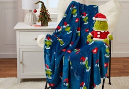 grinch holiday pillow and blanket sitting on a chair