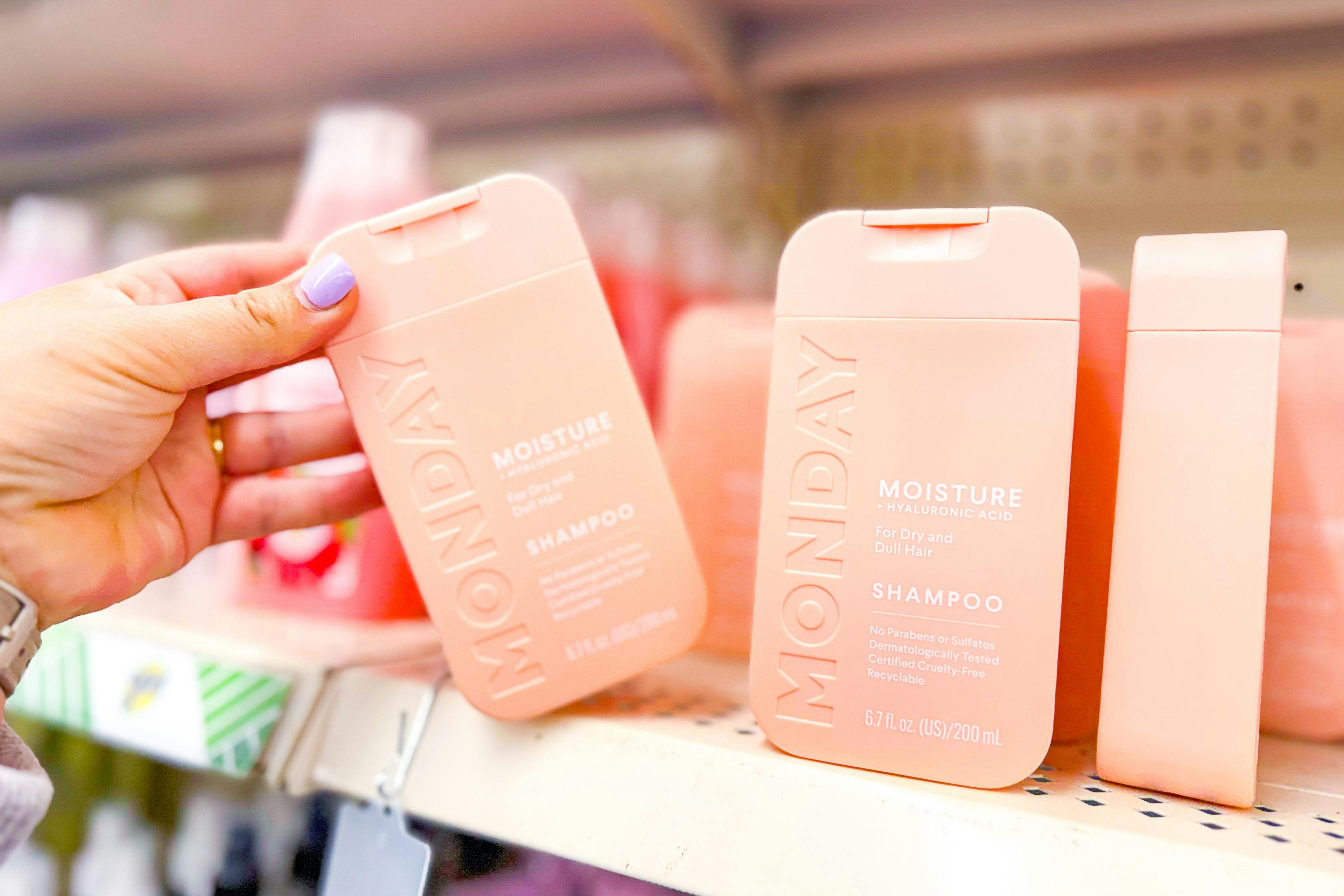 hand grabbing a bottle of monday shampoo