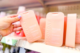 hand grabbing a bottle of monday shampoo