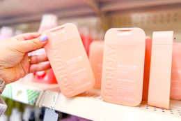 hand grabbing a bottle of monday shampoo