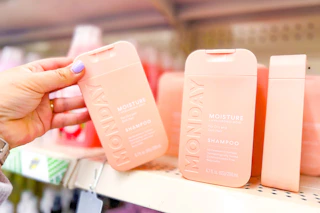 hand grabbing a bottle of monday shampoo